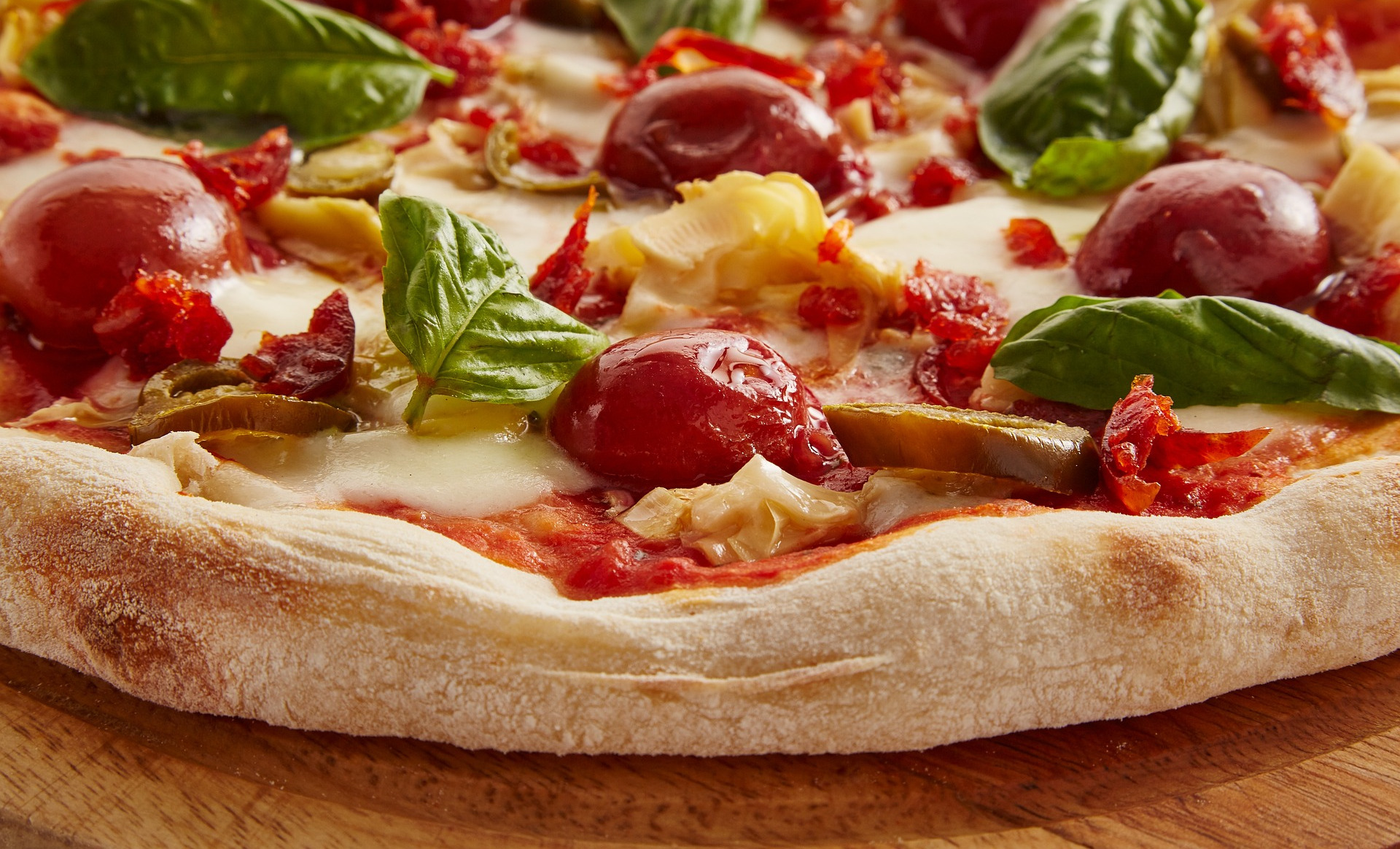 Frisch gebackene Pizza mit geschmolzenem Käse, Tomaten und Basilikumblättern auf knusprigem Rand.